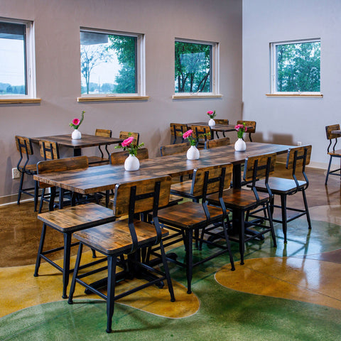 Dining area with wooden tables and chairs in a room with large windows.