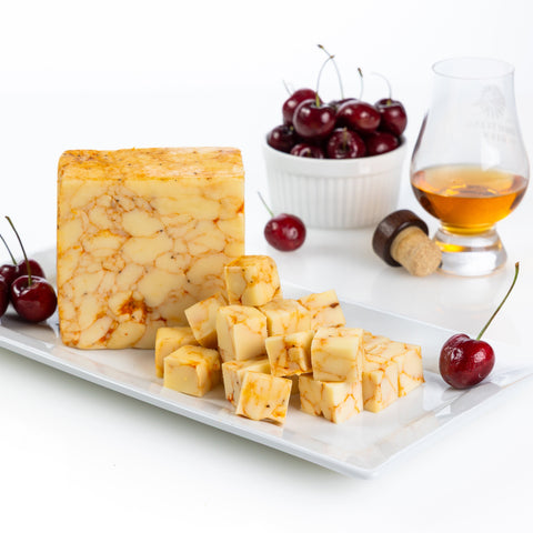 Cherry Bourbon Cheddar surrounded by dark red cherries and a glass of bourbon