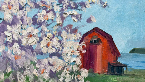 Red barn with cherry blossoms in the foreground against a blue sky.