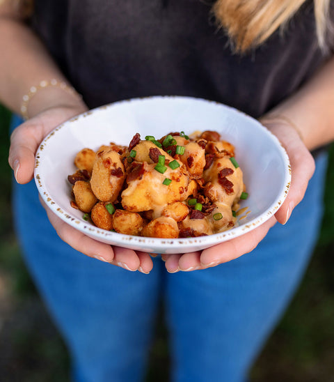 Person holding a bowl of Loaded Cheese Curds